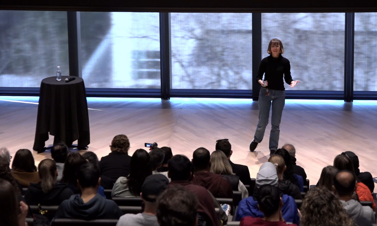 Heidi on stage gesturing toward an audience
